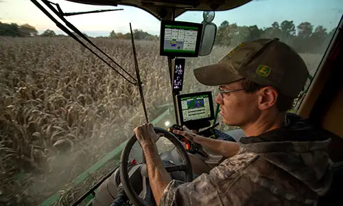 student driving a tractor in the corn field